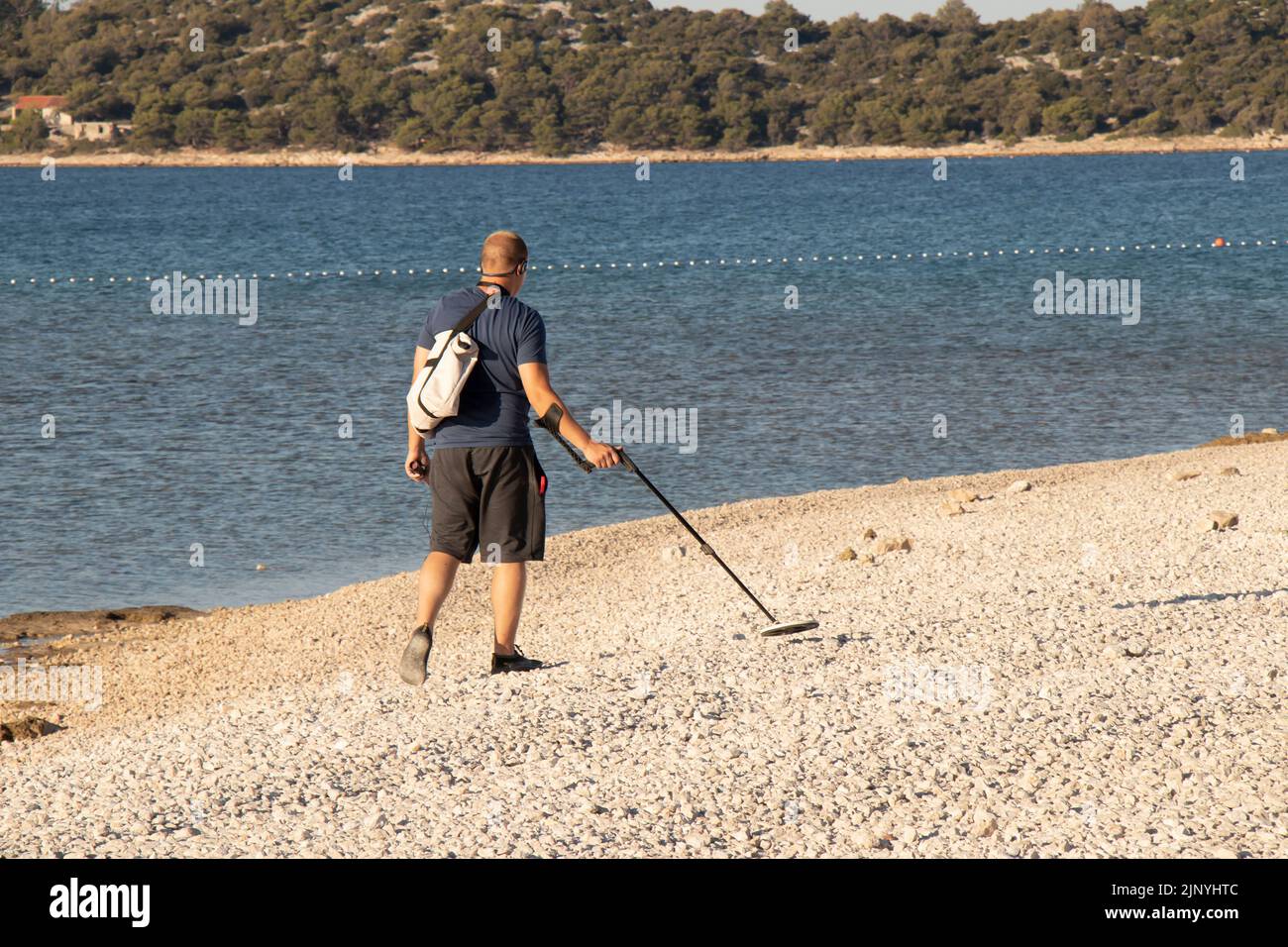Vodice, Croatie - 20 juillet 2022: Personne marchant sur la plage de galets vide à l'aide d'un détecteur de métal extérieur Banque D'Images
