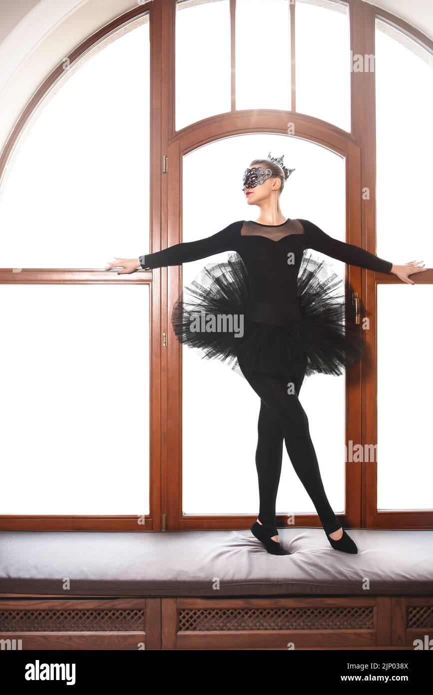 ballerine en robe de cygne noire sur fond de wgite. Jeune danseuse de ballet pratiquant avant la représentation en tutu noir, studio de danse classique, copie Banque D'Images