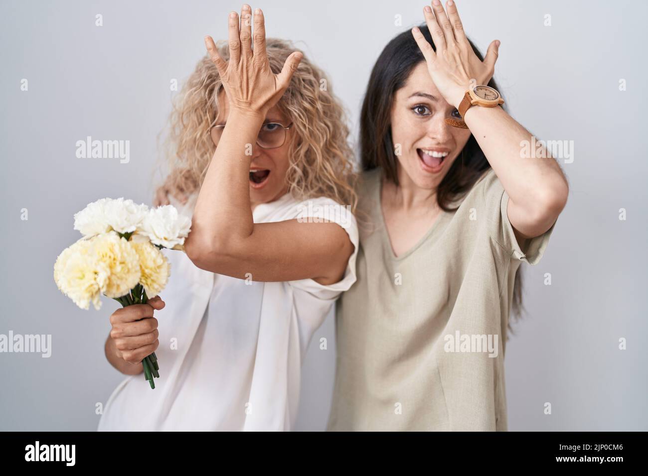 Mère et fille tenant le bouquet de fleurs blanches surpris avec la main sur la tête pour l'erreur, rappelez-vous erreur. oublié, mauvais concept de mémoire. Banque D'Images Mère et fille tenant le bouquet de fleurs blanches surpris avec la main sur la tête pour l'erreur, rappelez-vous erreur. oublié, mauvais concept de mémoire. Banque D'Images
