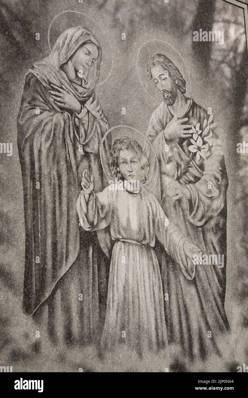 Religieux Joseph, Vierge Marie et enfants Jésus figures représentées sur un monument commémoratif en granit gris dans un cimetière. Banque D'Images