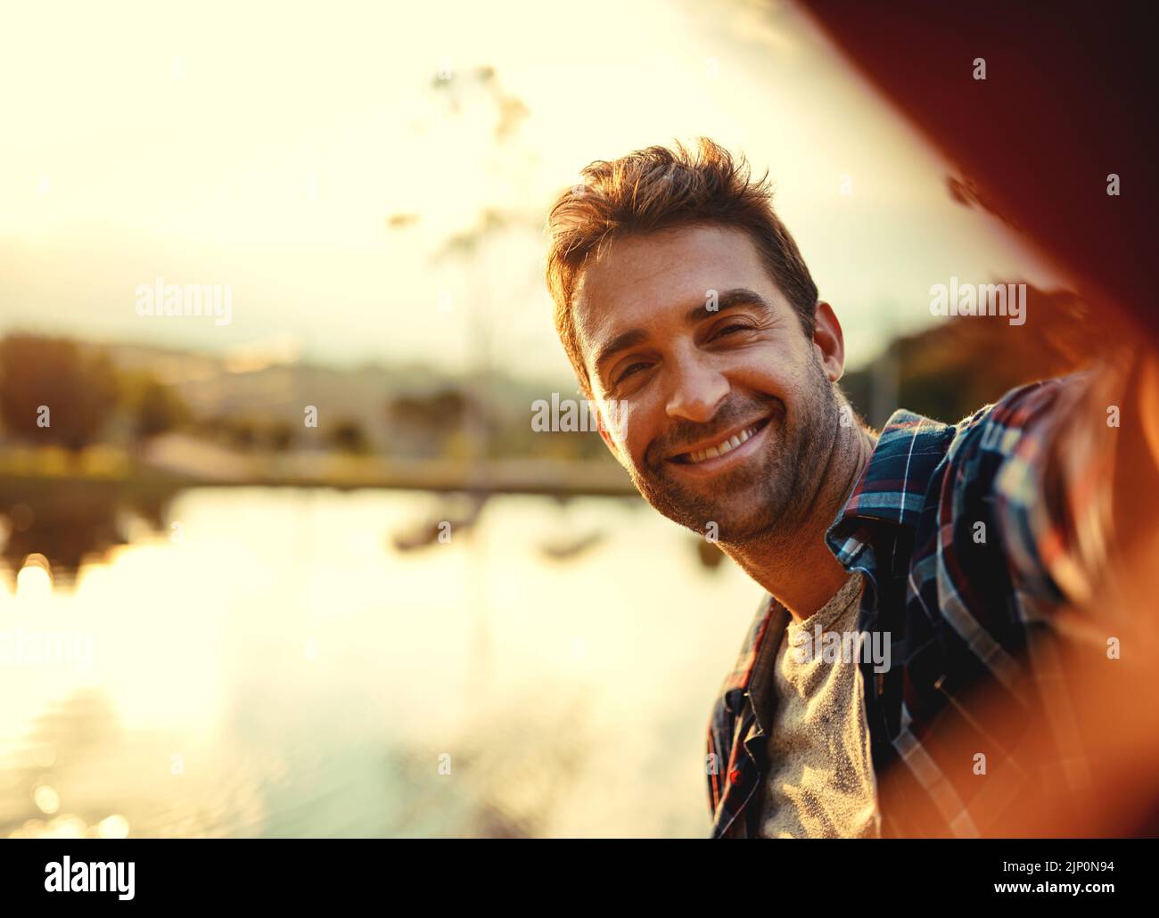 C'est génial ici. Portrait court d'un beau jeune homme prenant des selfies tout en passant la journée à un lac. Banque D'Images