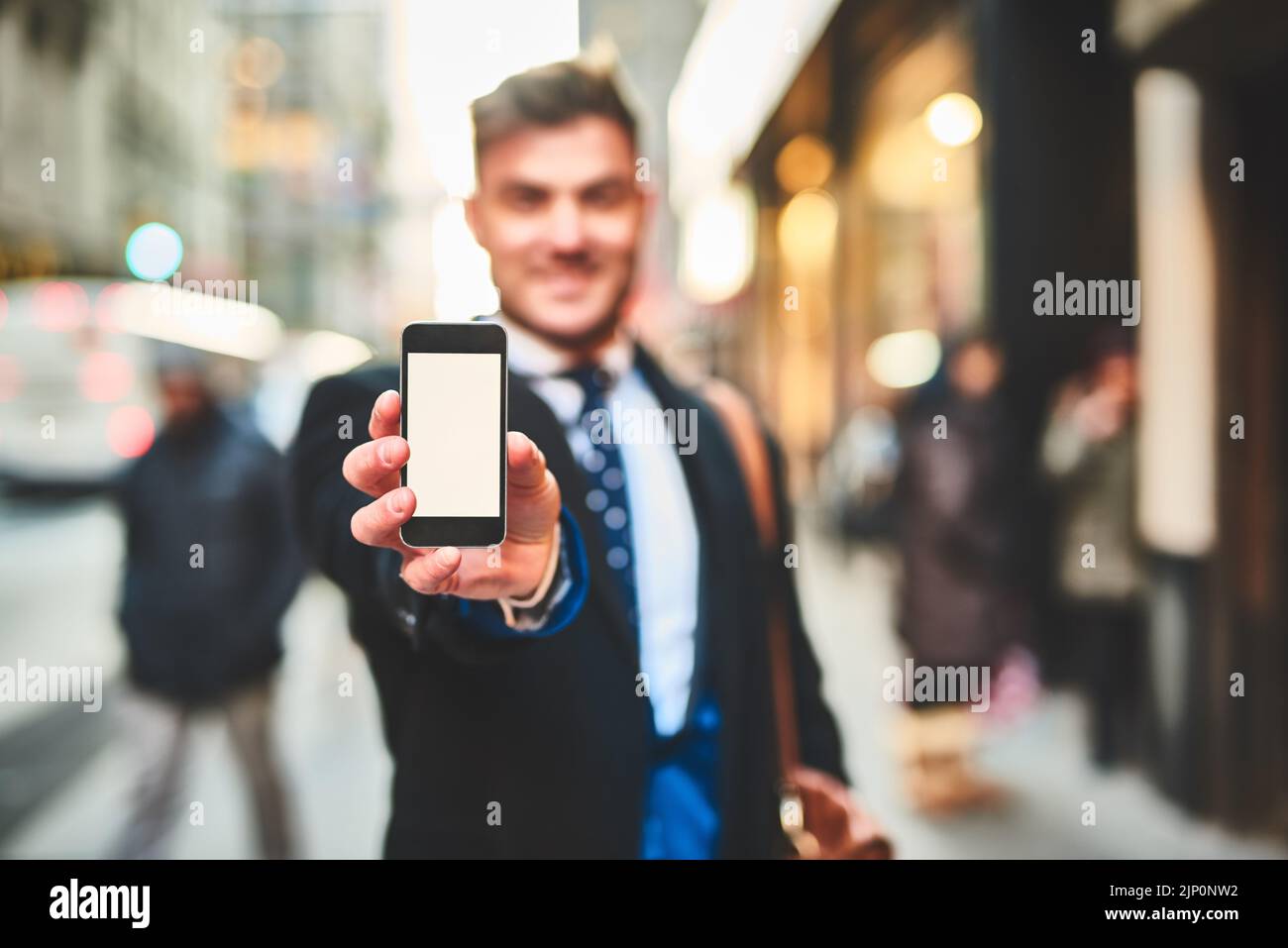 Regardez cette photo que j'ai prise de vous. Portrait d'un jeune homme joyeux tenant un téléphone portable et montrant l'écran à l'extérieur de l'appareil photo dans la ville Banque D'Images