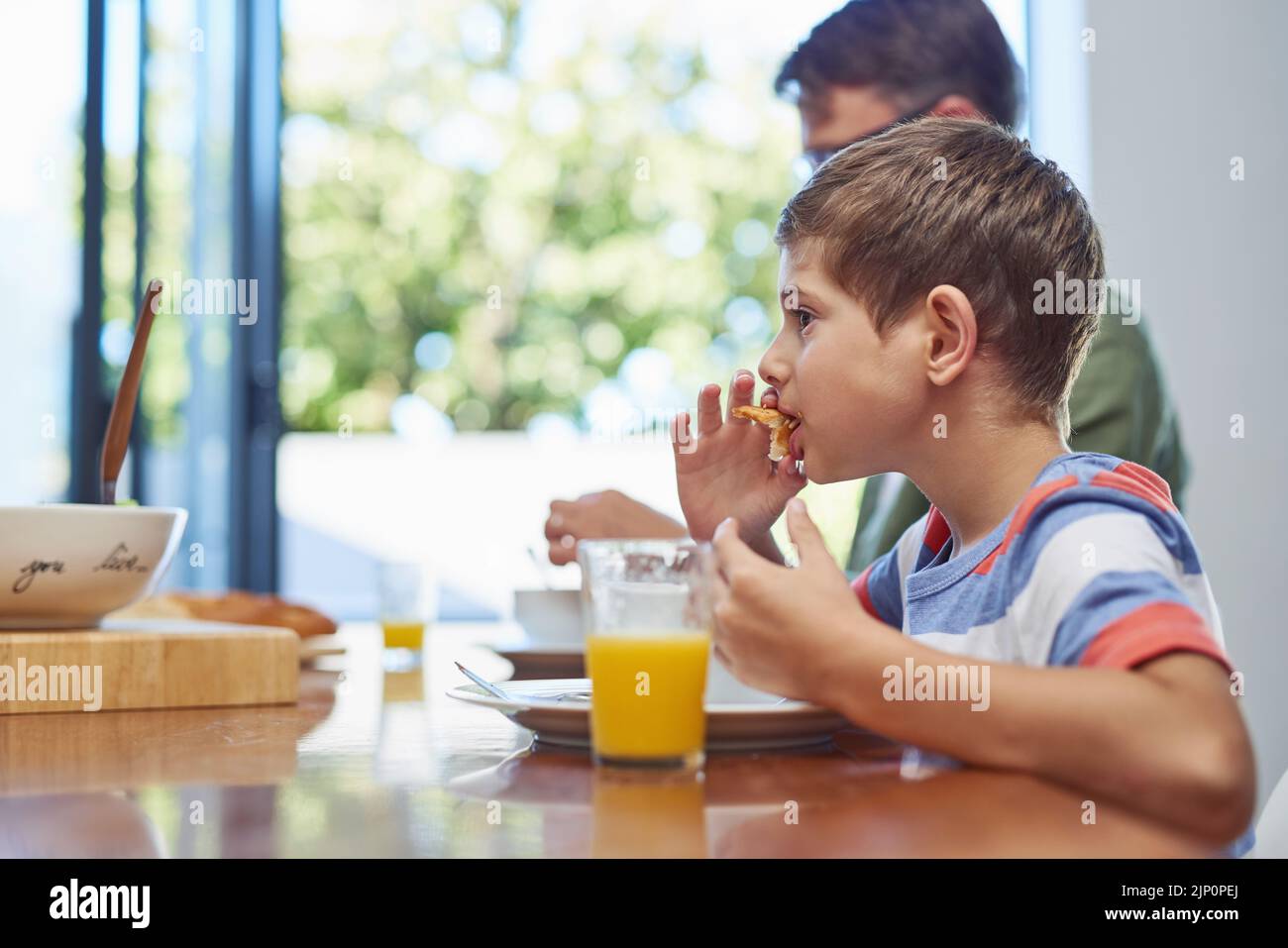 Un petit garçon qui apprécie un repas avec son père à la maison. Banque D'Images