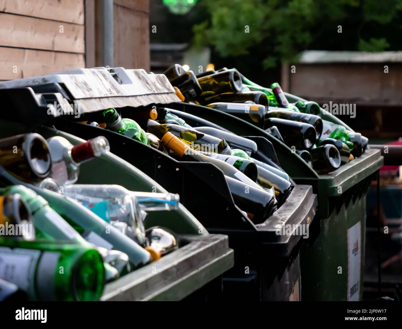 De nombreuses bouteilles en verre vides de différentes couleurs sont mises au rebut dans des récipients énormes. Beaucoup de déchets pour le recyclage dans l'arrière-cour d'un restaurant ou d'un bar. Banque D'Images