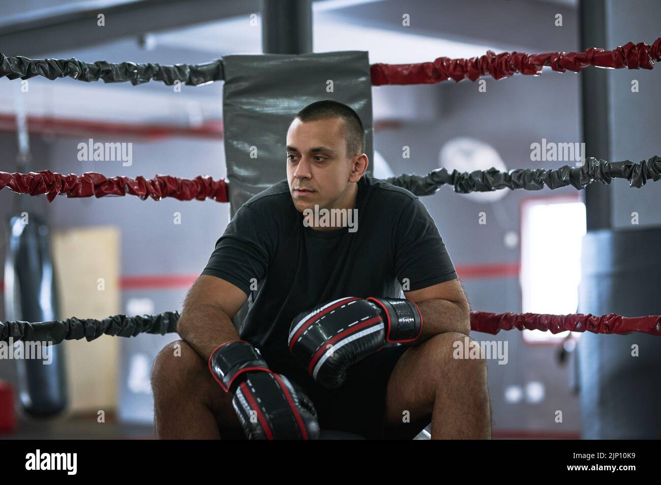 Se familiariser avec le ring. Un jeune athlète masculin assis dans le coin d'un ring de boxe. Banque D'Images