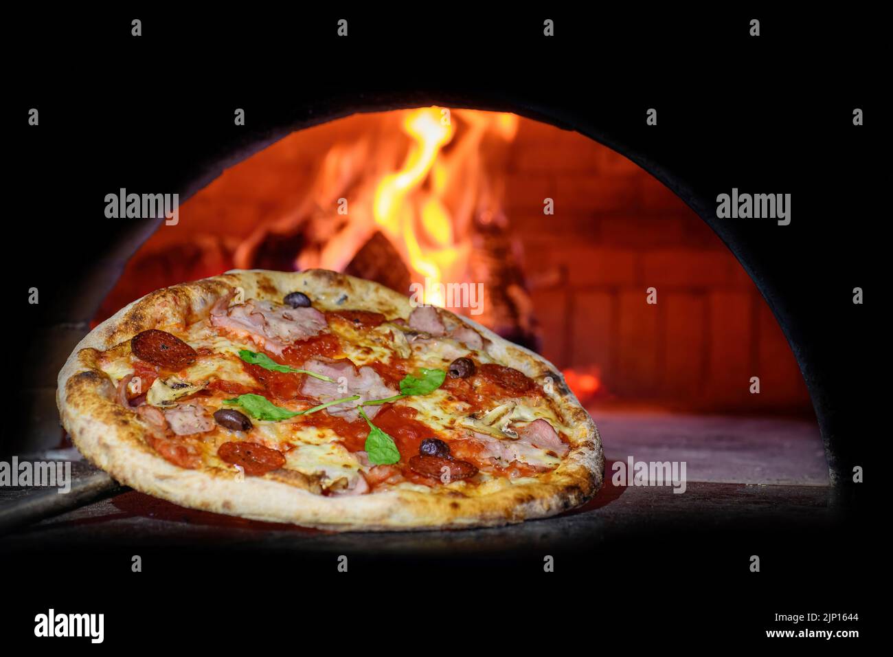 Fermez une délicieuse pizza italienne dans une pelle en mettant dans un four à bois Banque D'Images Fermez une délicieuse pizza italienne dans une pelle en mettant dans un four à bois Banque D'Images