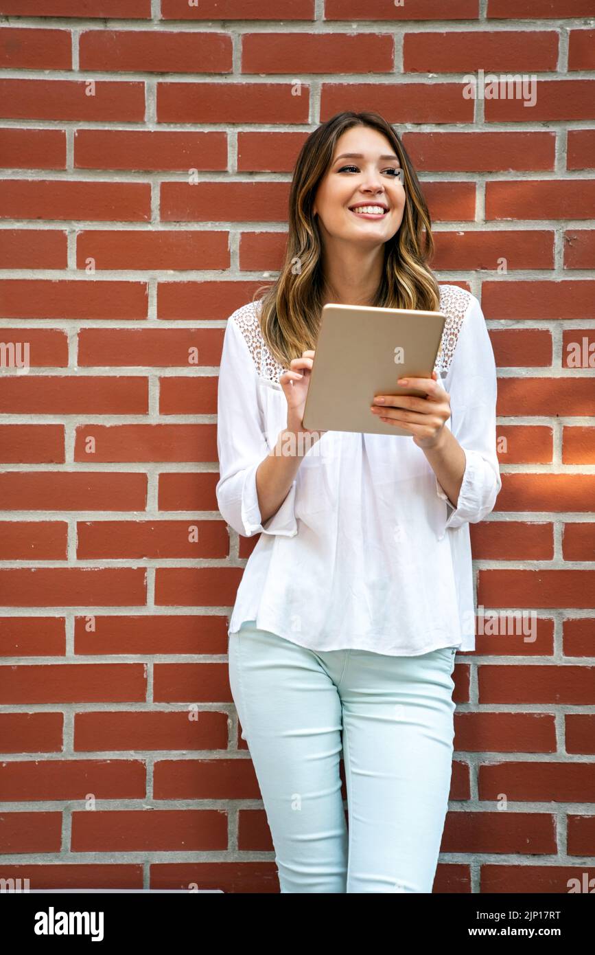 Belle jeune femme utilisant une tablette numérique et souriant Banque D'Images