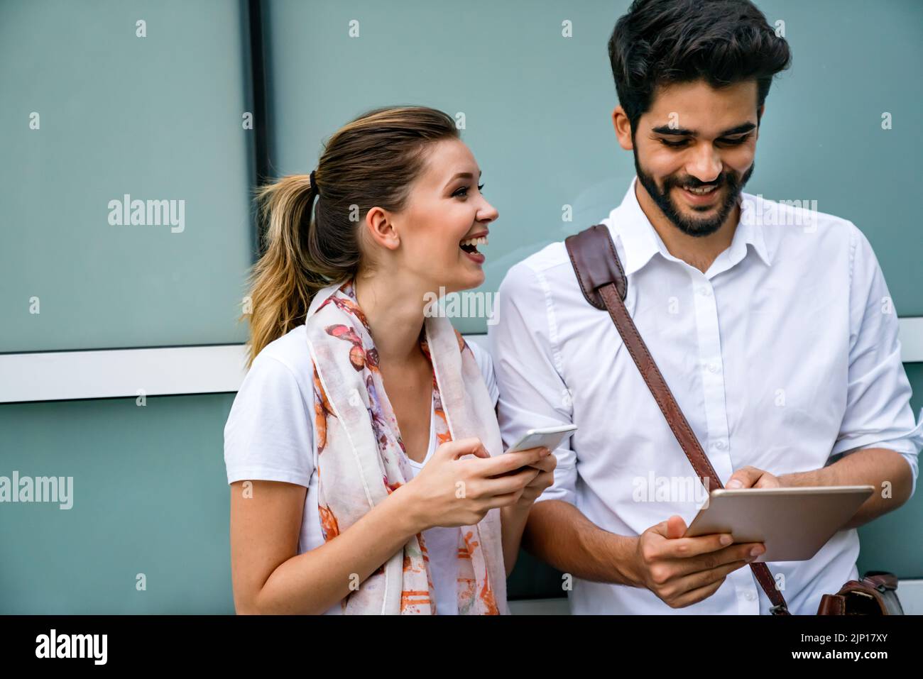 Homme d'affaires et femme heureux avec des appareils numériques à l'extérieur. Concept de bonheur des gens d'affaires Banque D'Images