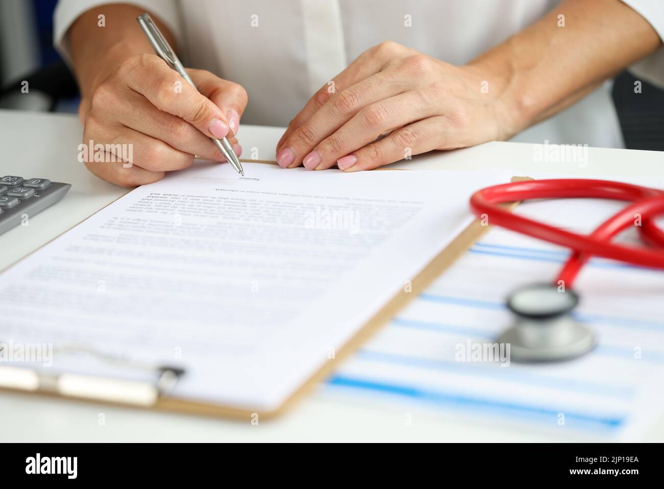 Femme médecin dans la robe médicale mettre signe sur le presse-papiers avec des documents Banque D'Images