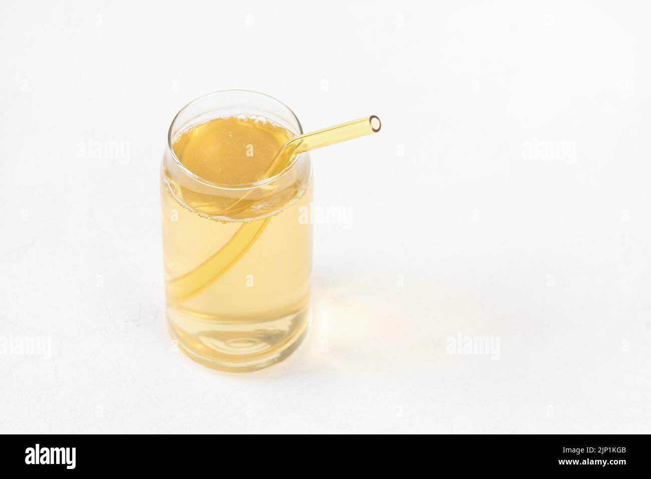 Boisson fermentée faite maison au kombucha dans du verre et paille réutilisable de couleur écologique sur fond blanc. Boisson probiotique heathy avec bulles. Boissons non alcoolisées en été. Copier l'espace Banque D'Images