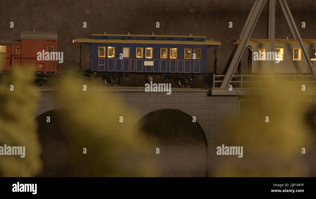 Le modèle de chemin de fer se déplace sur un pont. Train de jouets avec wagons de passagers roulant sur la route miniature. Jouets pour enfants. Banque D'Images