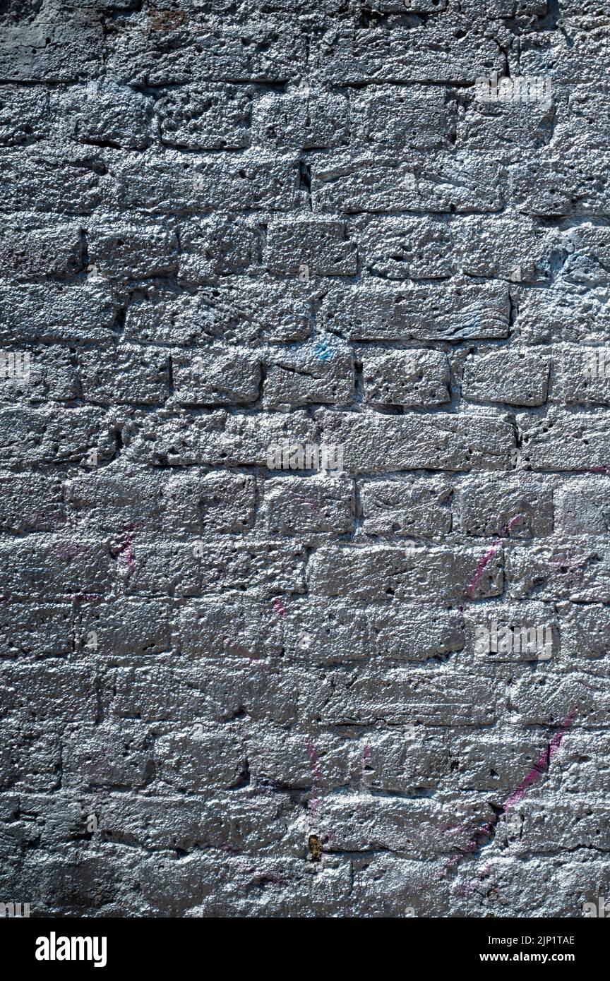 Un mur de briques pulvérisé de peinture argentée. Convient à un arrière-plan ou une texture Banque D'Images