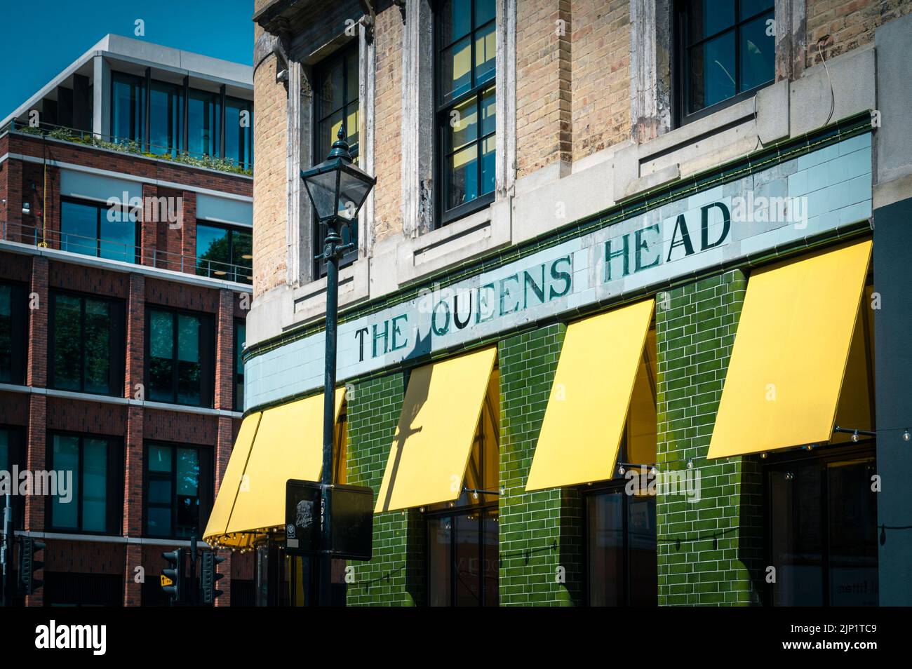 Le pub Queens Head près de Spitalfields London uk avec des stores jaunes colorés et des murs carrelés de vert Banque D'Images