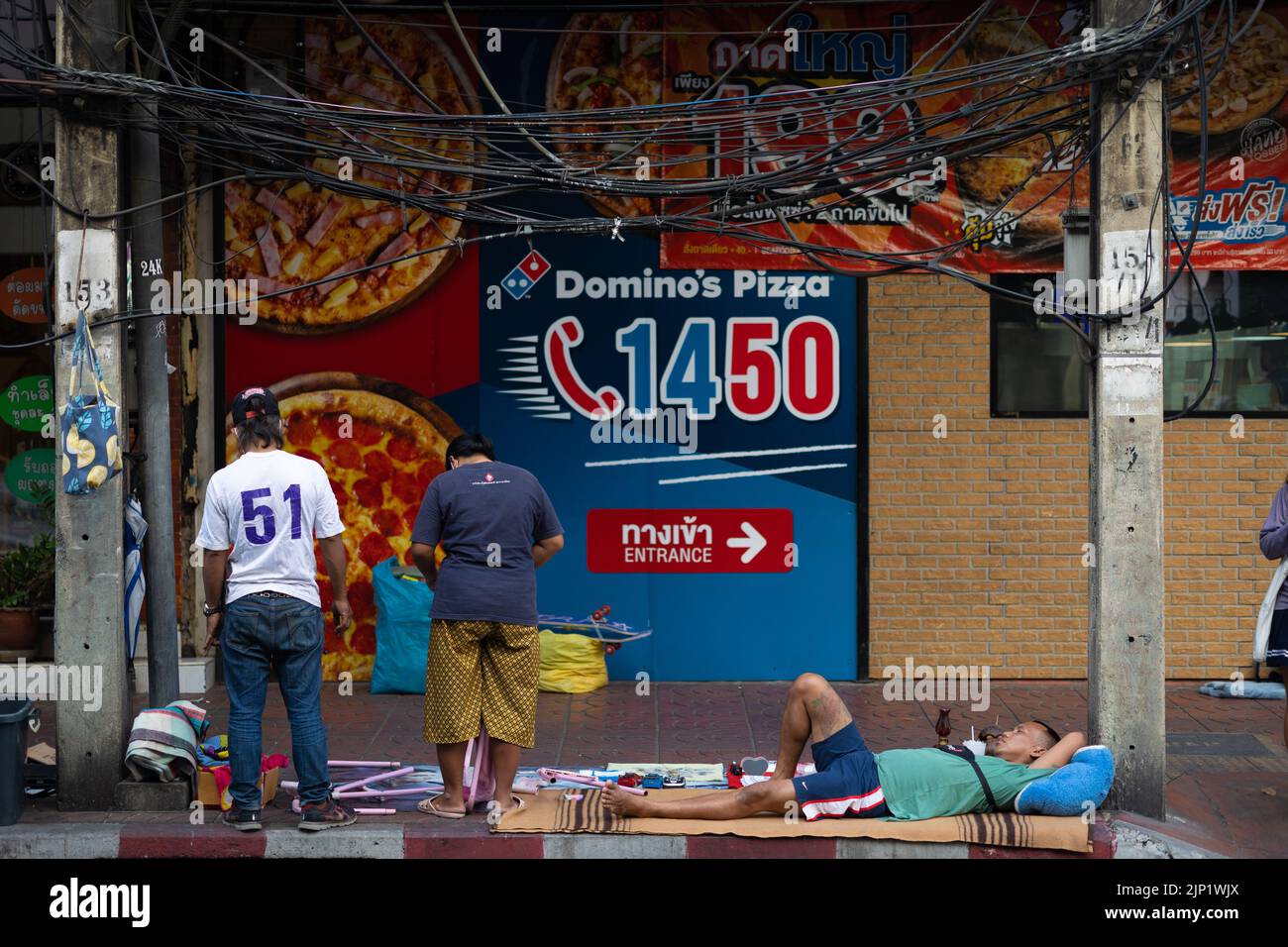 BANGKOK, THAÏLANDE - 11 DÉCEMBRE 2021 : Un homme sans domicile se repose sur le trottoir dans le quartier de Chinatown. Banque D'Images