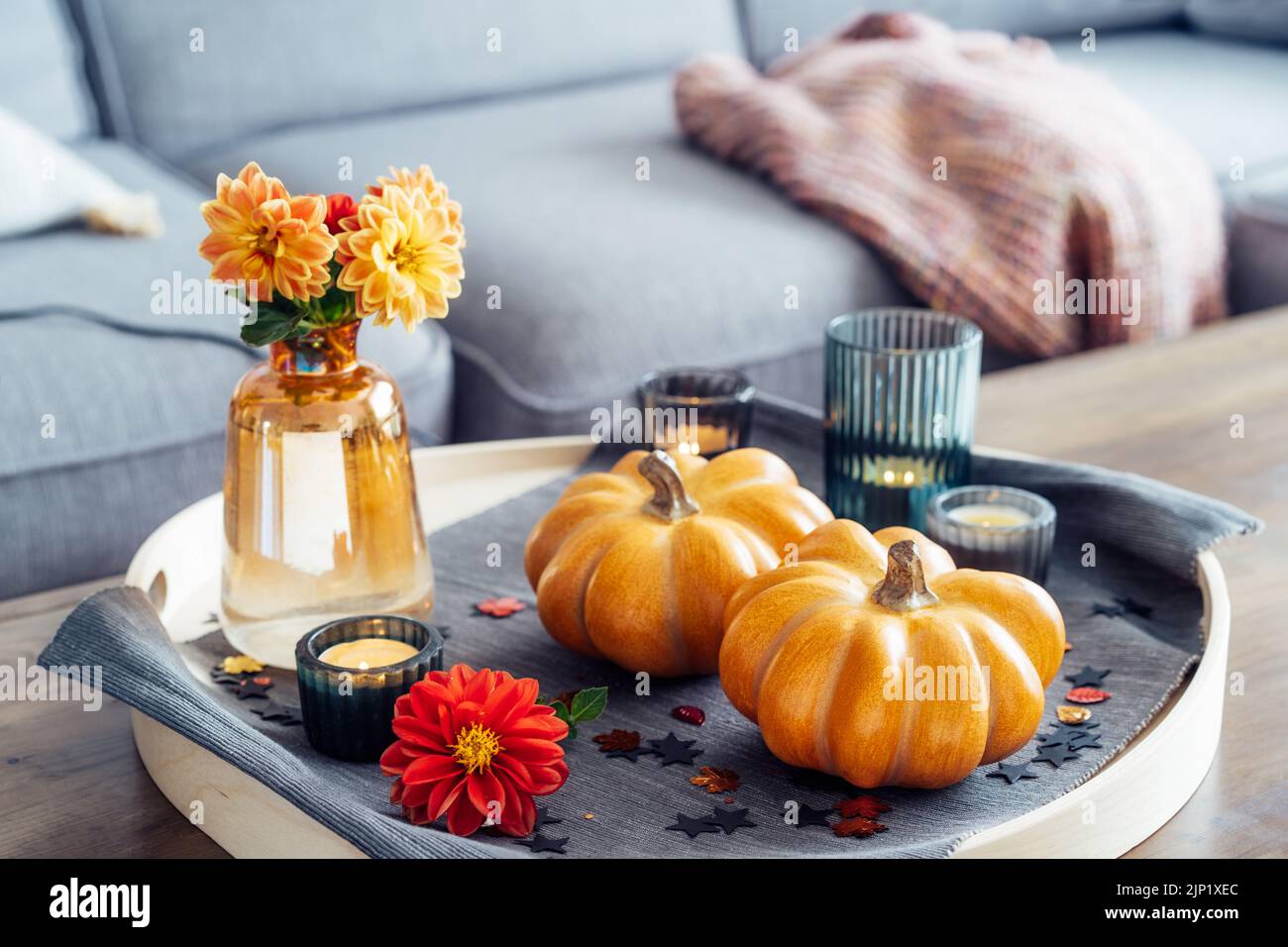 Automne, ambiance chaleureuse composition pour un décor de style maison en hygge. Petits citrouilles, bougies allumées et fleurs de dahlia fraîches sur le plateau avec une serviette grise sur le Banque D'Images Automne, ambiance chaleureuse composition pour un décor de style maison en hygge. Petits citrouilles, bougies allumées et fleurs de dahlia fraîches sur le plateau avec une serviette grise sur le Banque D'Images