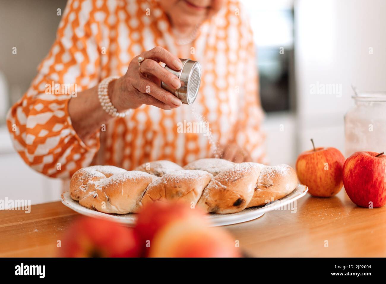Bonne femme âgée avec du pain tressé sucré fait maison avec des raisins secs. Gros plan. Banque D'Images