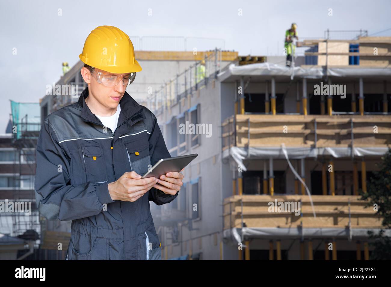 Concevoir avec une tablette numérique à l'arrière-plan d'un bâtiment en construction Banque D'Images