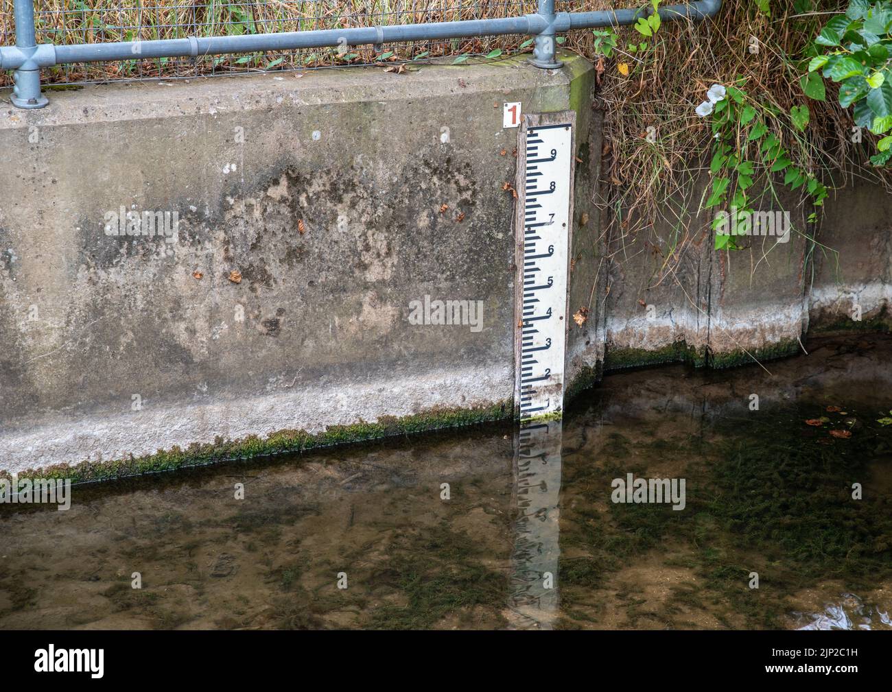 Indicateur de niveau d'eau de rivière à lignes noires et blanches, avec faible niveau d'eau. Banque D'Images