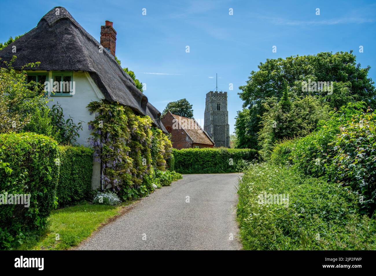 Une scène de village anglais avec un cottage de chaume et l'église du village Banque D'Images