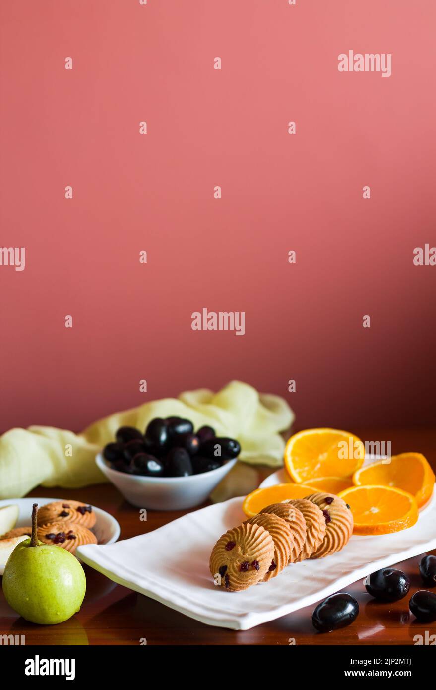 Plateau de fruits avec un mélange d'oranges fraîches, juteuses, sucrées, poires, jamun également appelé baies de prune Java et biscuits d'avoine placés sur une table en bois sombre comme b Banque D'Images