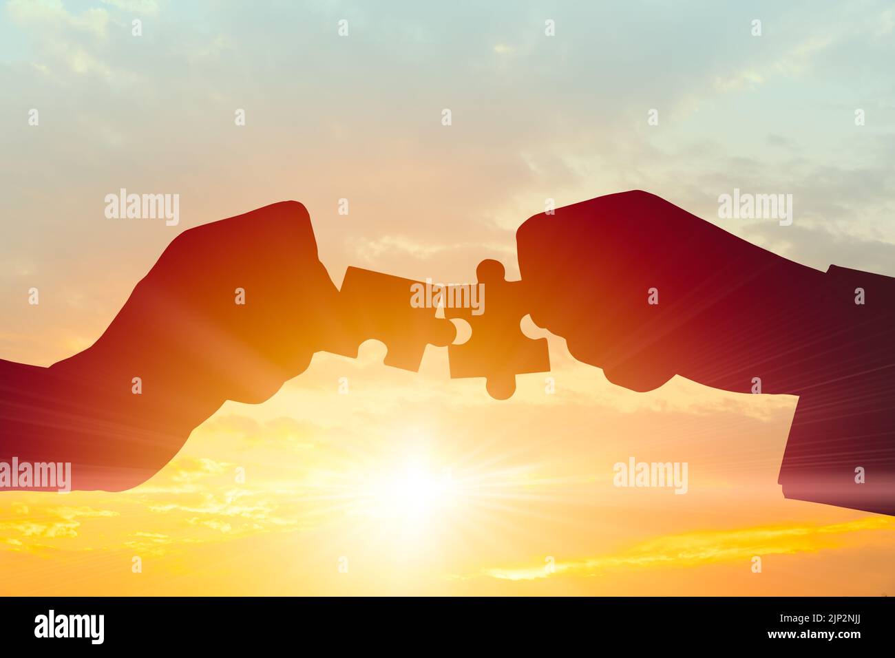 Business Teamwork, rejoindre le concept de partenariat et de coopération. Silhouette de deux mains reliant deux pièces de puzzle se connectent sur le ciel du matin. Banque D'Images
