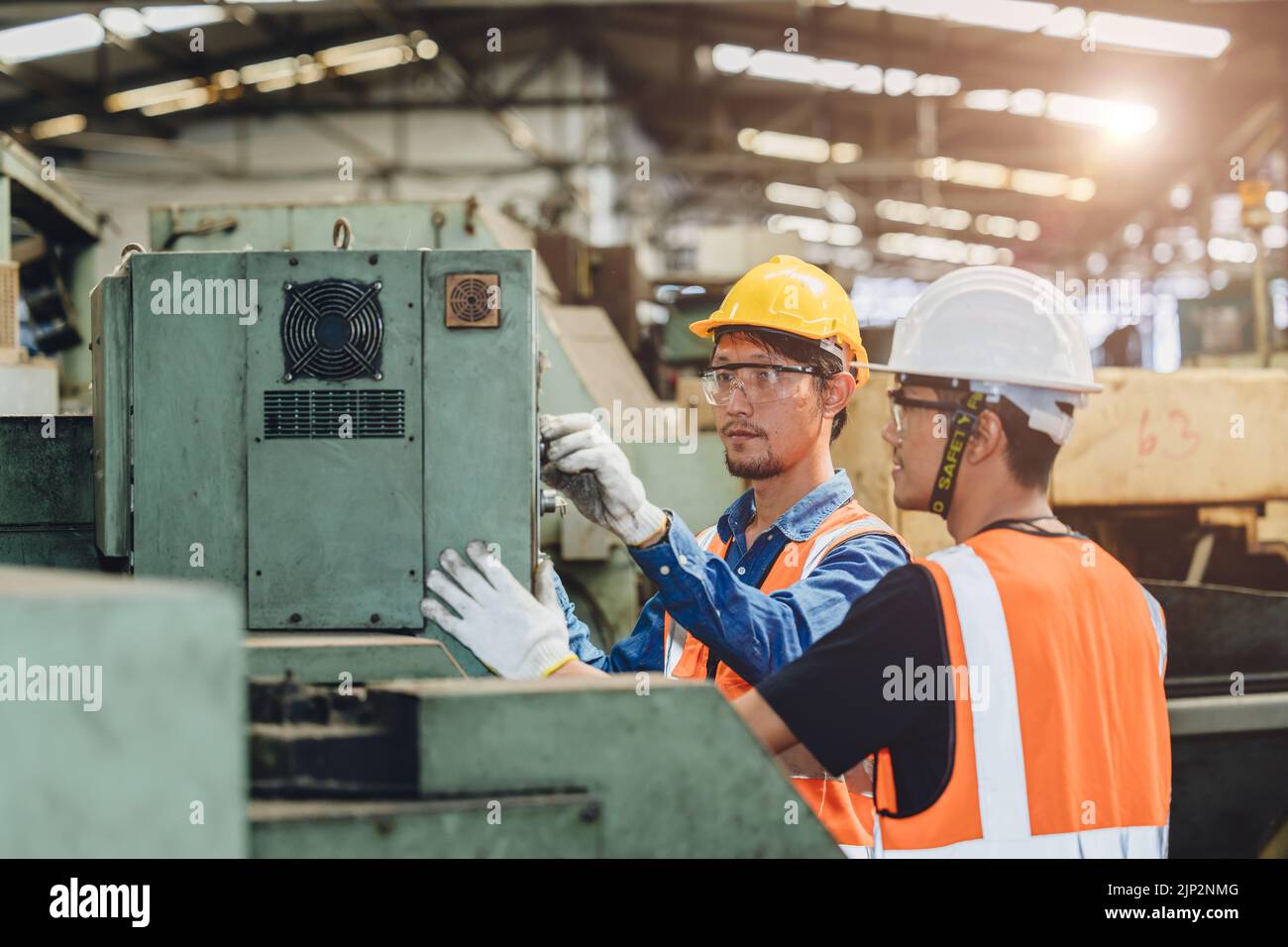 Un travailleur de l'industrie travaille ensemble à la formation de jeunes conducteurs de machines neuves dans une usine de métaux. Banque D'Images