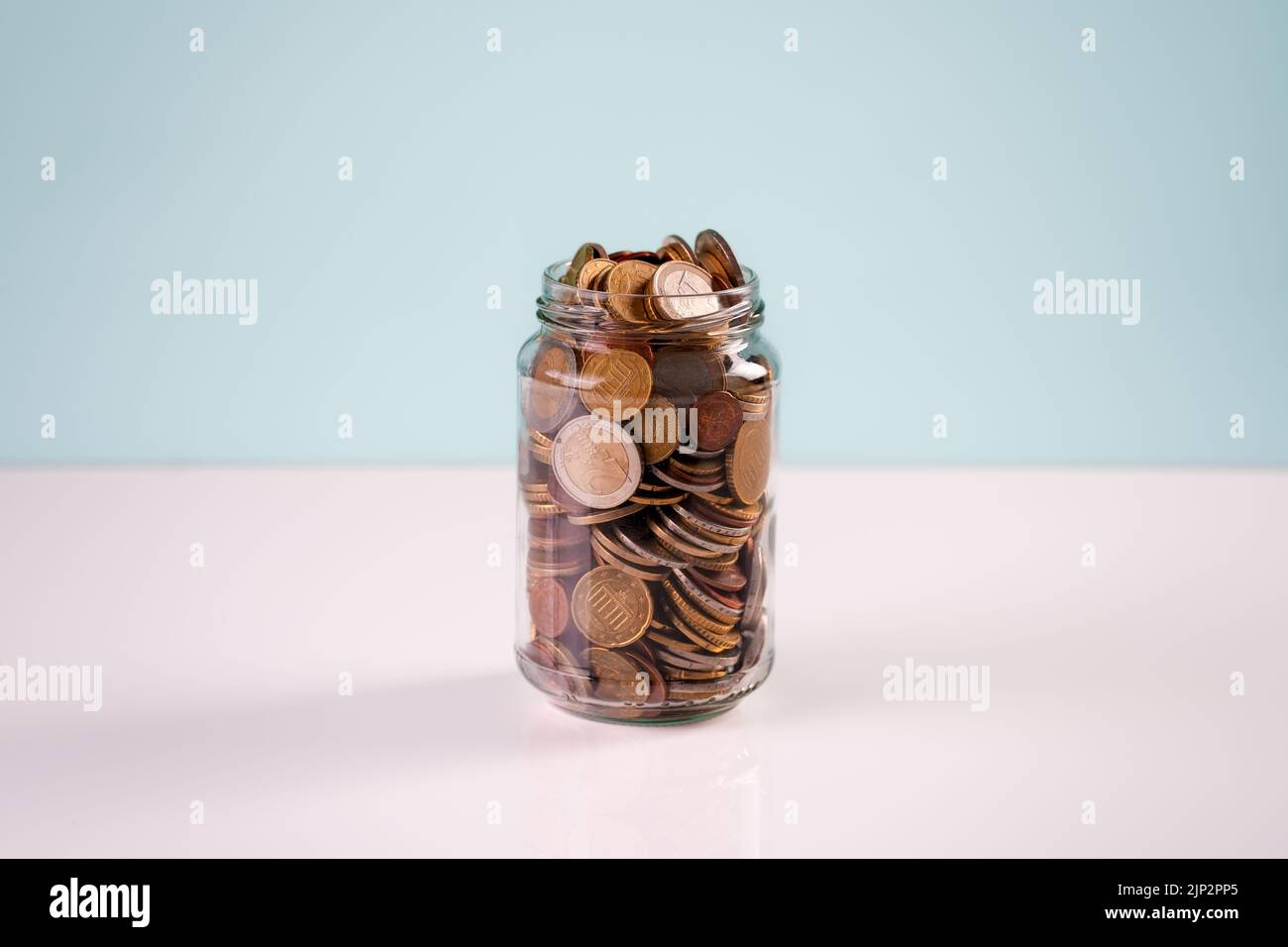 Une pile de pièces de monnaie dans un pot en verre sur une table Banque D'Images