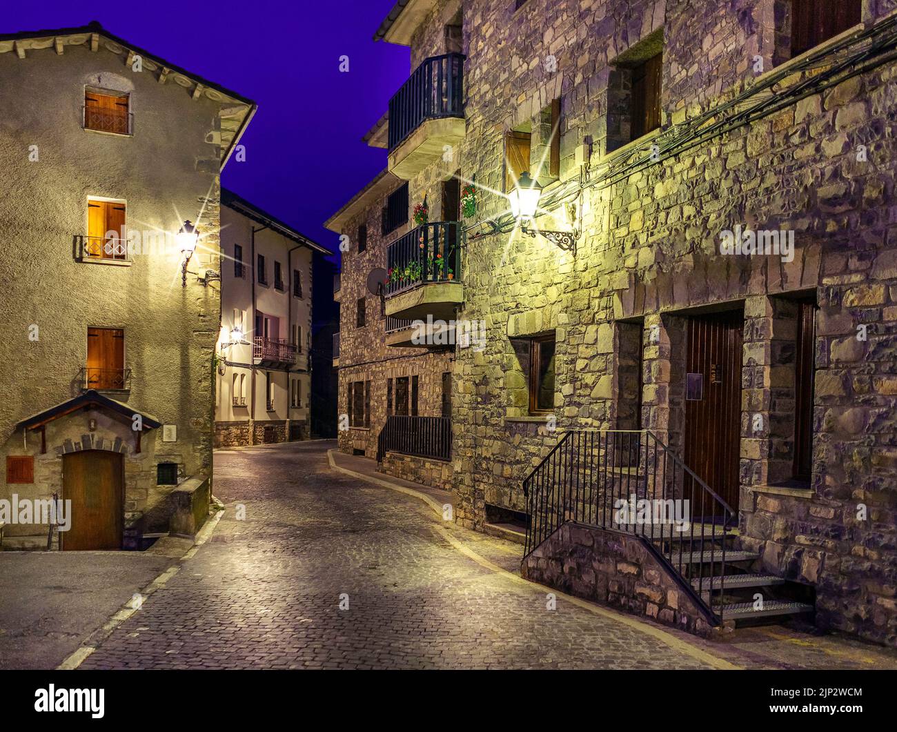 Rue du village de montagne la nuit. Architecture de maisons en pierre, balcons avec fleurs et allées illuminées. Torla Ordesa. Banque D'Images