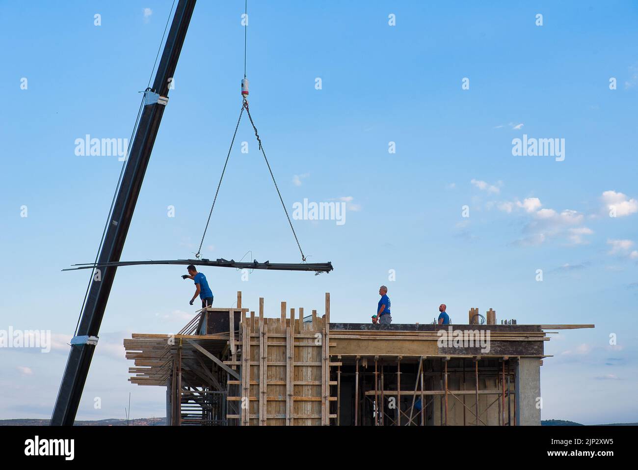 une grue automotrice décharge les matériaux de construction dans un immeuble construit Banque D'Images
