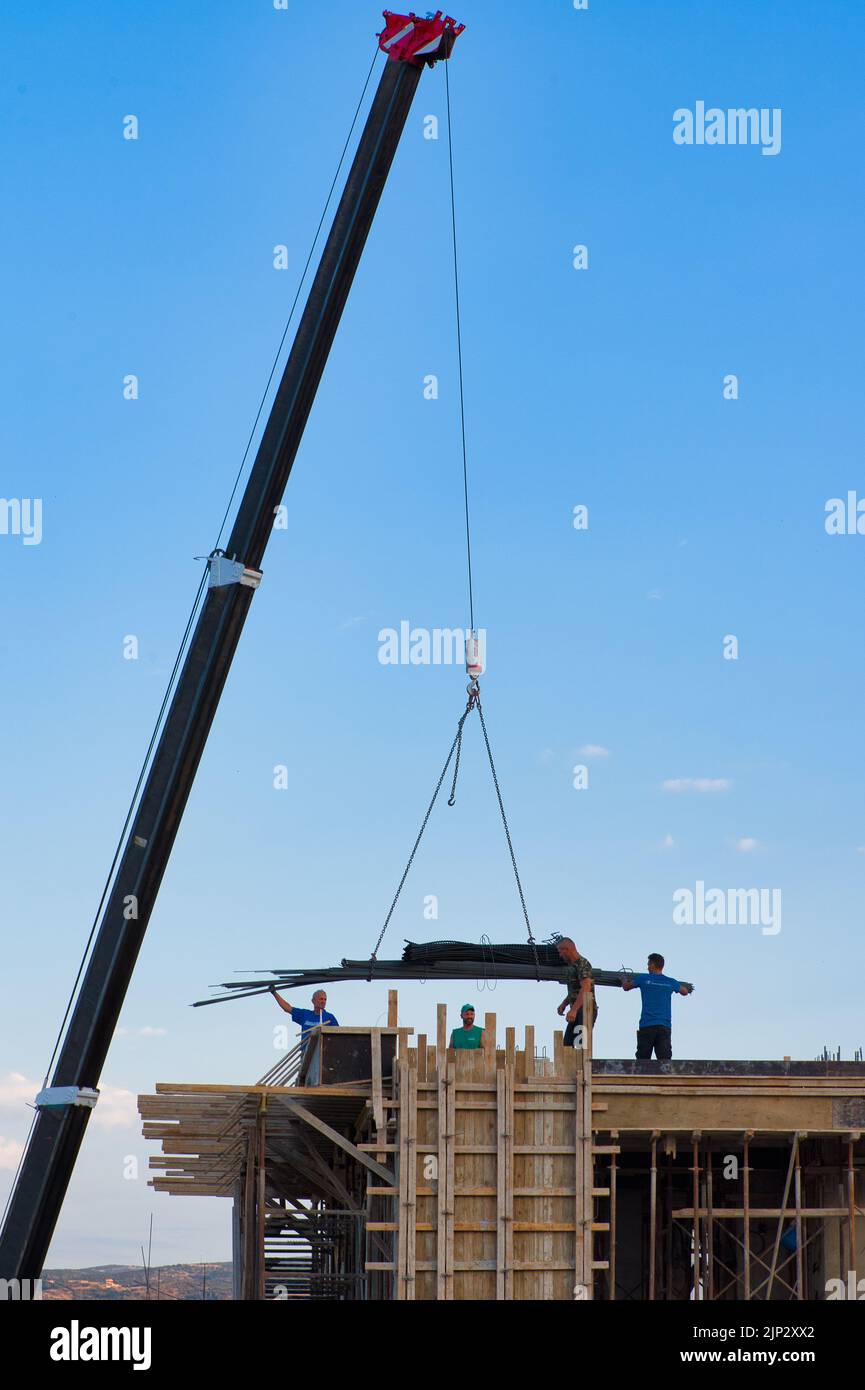 les ouvriers de la construction déchargent les matériaux de construction d'une grue Banque D'Images