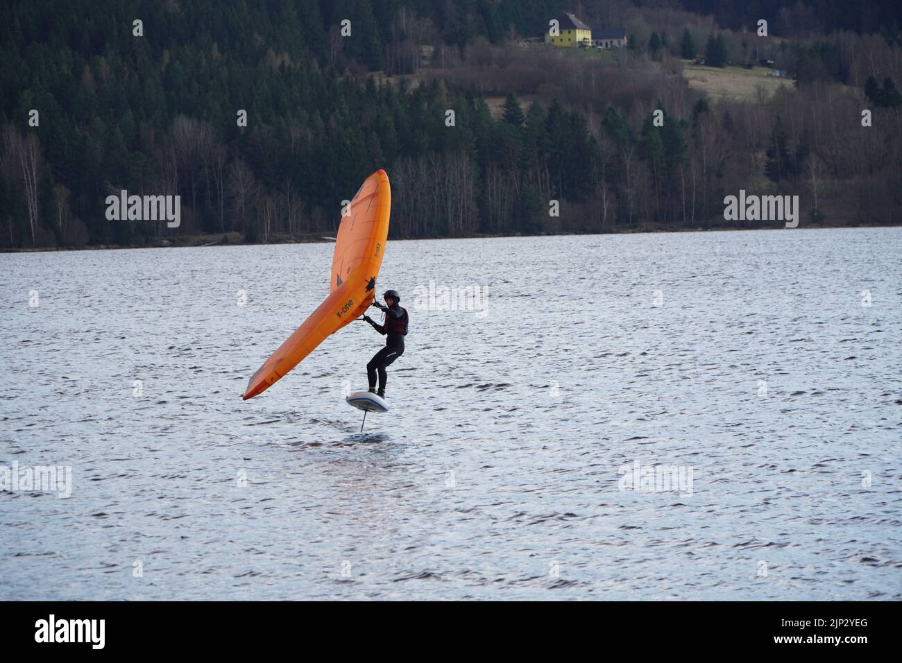 Un homme sur la planche de surf à feuilles électriques de cerf-volant en arrière-plan d'arbres Banque D'Images