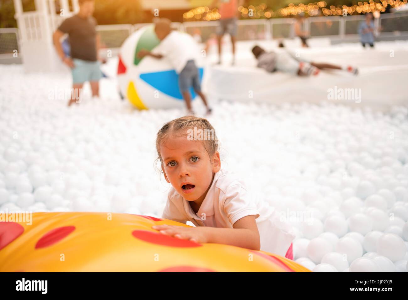 Bonne petite fille jouant des boules de plastique blanc piscine dans le parc d'attractions. Aire de jeux pour les enfants. Loisirs actifs pour les enfants. Banque D'Images