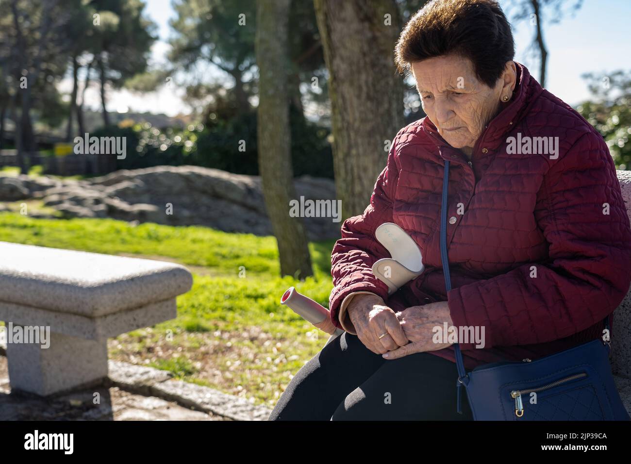 femme âgée de 90 ans assise sur un banc et triste regardant le sol. Banque D'Images