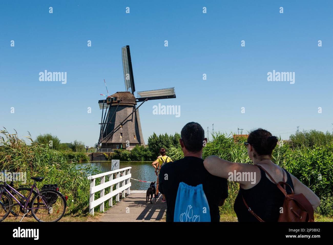 Kinderdijk, pays-Bas. 13th août 2022. Un couple est vu regardant l'un des moulins à vent de l'ombre sur une journée très chaude. Dans la belle région riche en eau près de Dordrecht, vous trouverez les moulins à vent de Kinderdijk. Construits vers 1740, ces 19 magnifiques moulins à vent font partie d'un plus grand système de gestion de l'eau pour éviter les inondations. Aujourd'hui, ils symbolisent la gestion de l'eau aux pays-Bas et, en 1997, ils ont été déclarés site du patrimoine mondial de l'UNESCO. Chaque année, des milliers de touristes du monde entier visitent ce lieu emblématique. Crédit : SOPA Images Limited/Alamy Live News Banque D'Images