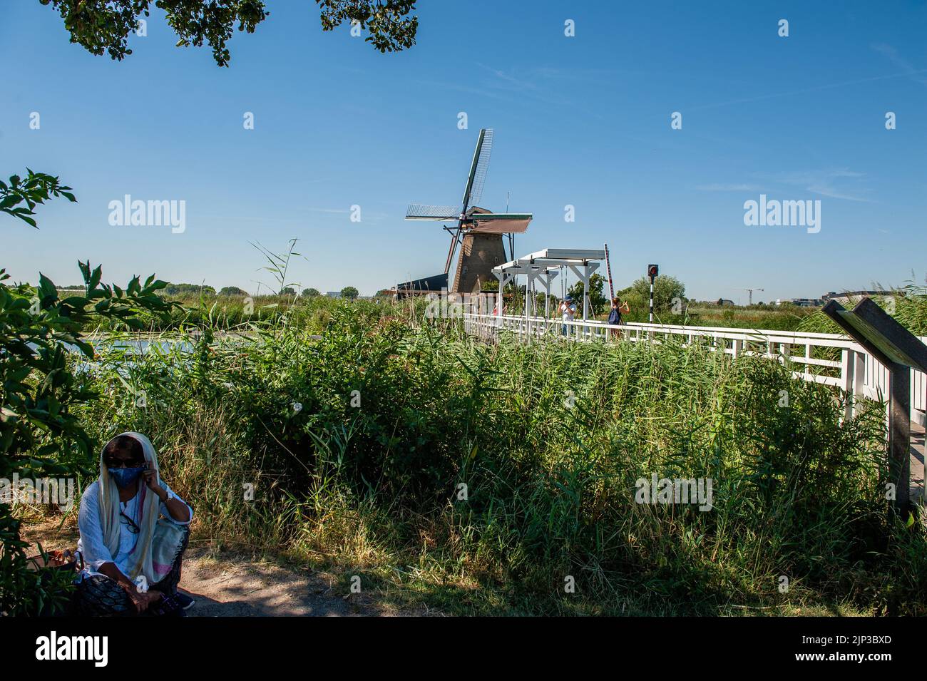 Kinderdijk, pays-Bas. 13th août 2022. Une femme indienne est vue prendre une pause lors de sa visite aux moulins à vent. Dans la belle région riche en eau près de Dordrecht, vous trouverez les moulins à vent de Kinderdijk. Construits vers 1740, ces 19 magnifiques moulins à vent font partie d'un plus grand système de gestion de l'eau pour éviter les inondations. Aujourd'hui, ils symbolisent la gestion de l'eau aux pays-Bas et, en 1997, ils ont été déclarés site du patrimoine mondial de l'UNESCO. Chaque année, des milliers de touristes du monde entier visitent ce lieu emblématique. Crédit : SOPA Images Limited/Alamy Live News Banque D'Images