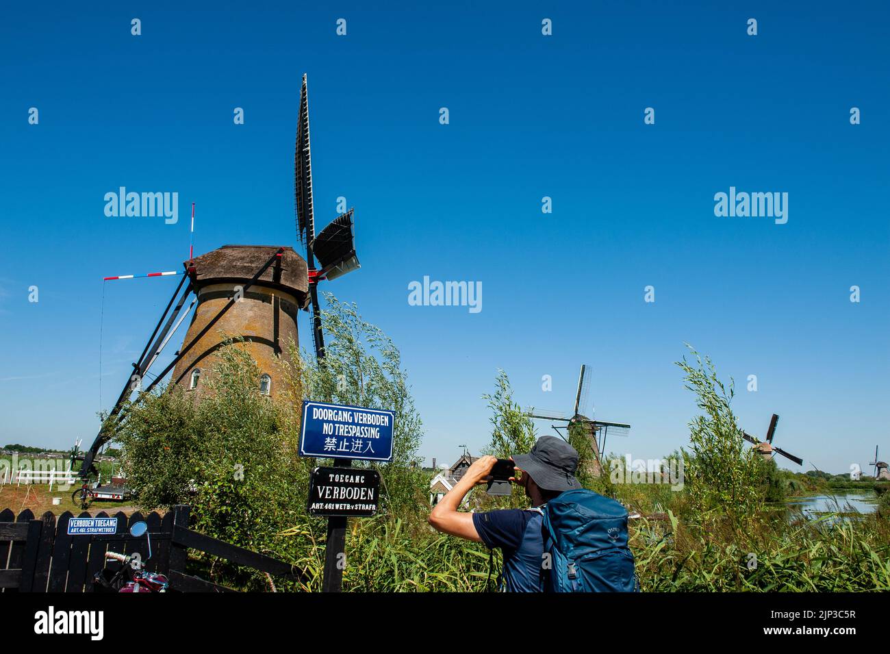 Kinderdijk, pays-Bas. 13th août 2022. Un homme est vu prendre une photo de l'un des moulins à vent emblématiques. Dans la belle région riche en eau près de Dordrecht, vous trouverez les moulins à vent de Kinderdijk. Construits vers 1740, ces 19 magnifiques moulins à vent font partie d'un plus grand système de gestion de l'eau pour éviter les inondations. Aujourd'hui, ils symbolisent la gestion de l'eau aux pays-Bas et, en 1997, ils ont été déclarés site du patrimoine mondial de l'UNESCO. Chaque année, des milliers de touristes du monde entier visitent ce lieu emblématique. Crédit : SOPA Images Limited/Alamy Live News Banque D'Images