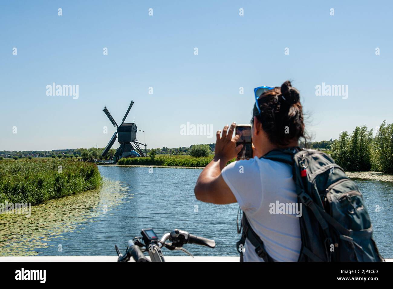 Kinderdijk, pays-Bas. 13th août 2022. On voit un homme prendre une photo avec son téléphone portable de l'un des moulins à vent. Dans la belle région riche en eau près de Dordrecht, vous trouverez les moulins à vent de Kinderdijk. Construits vers 1740, ces 19 magnifiques moulins à vent font partie d'un plus grand système de gestion de l'eau pour éviter les inondations. Aujourd'hui, ils symbolisent la gestion de l'eau aux pays-Bas et, en 1997, ils ont été déclarés site du patrimoine mondial de l'UNESCO. Chaque année, des milliers de touristes du monde entier visitent ce lieu emblématique. Crédit : SOPA Images Limited/Alamy Live News Banque D'Images