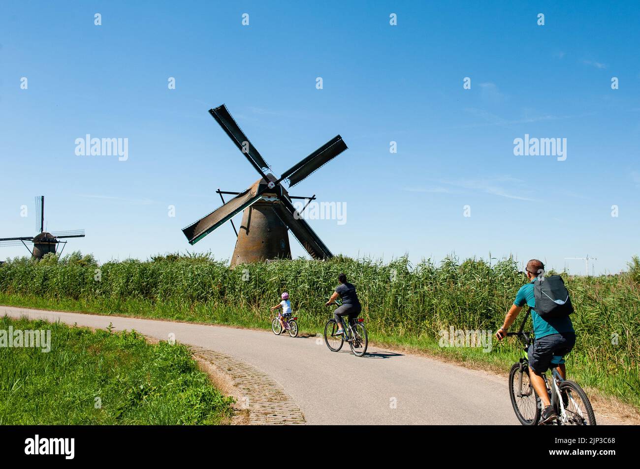 Kinderdijk, pays-Bas. 13th août 2022. Un groupe de personnes sur leurs vélos passe devant les moulins à vent. Dans la belle région riche en eau près de Dordrecht, vous trouverez les moulins à vent de Kinderdijk. Construits vers 1740, ces 19 magnifiques moulins à vent font partie d'un plus grand système de gestion de l'eau pour éviter les inondations. Aujourd'hui, ils symbolisent la gestion de l'eau aux pays-Bas et, en 1997, ils ont été déclarés site du patrimoine mondial de l'UNESCO. Chaque année, des milliers de touristes du monde entier visitent ce lieu emblématique. Crédit : SOPA Images Limited/Alamy Live News Banque D'Images