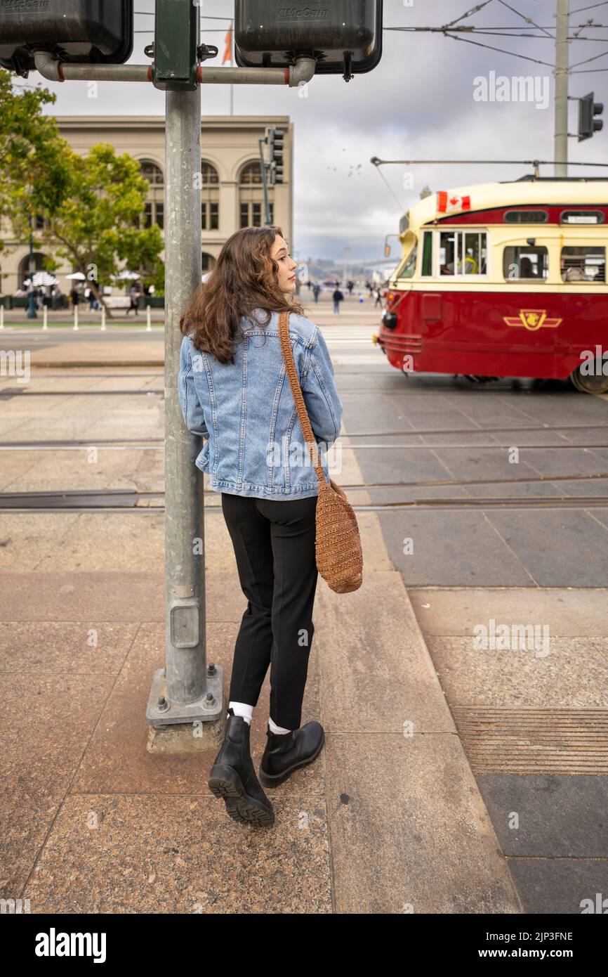 Portrait non posé d'une jeune femme qui attend de traverser une rue animée du centre-ville | Veste en Jean | San Francisco Wharf Banque D'Images