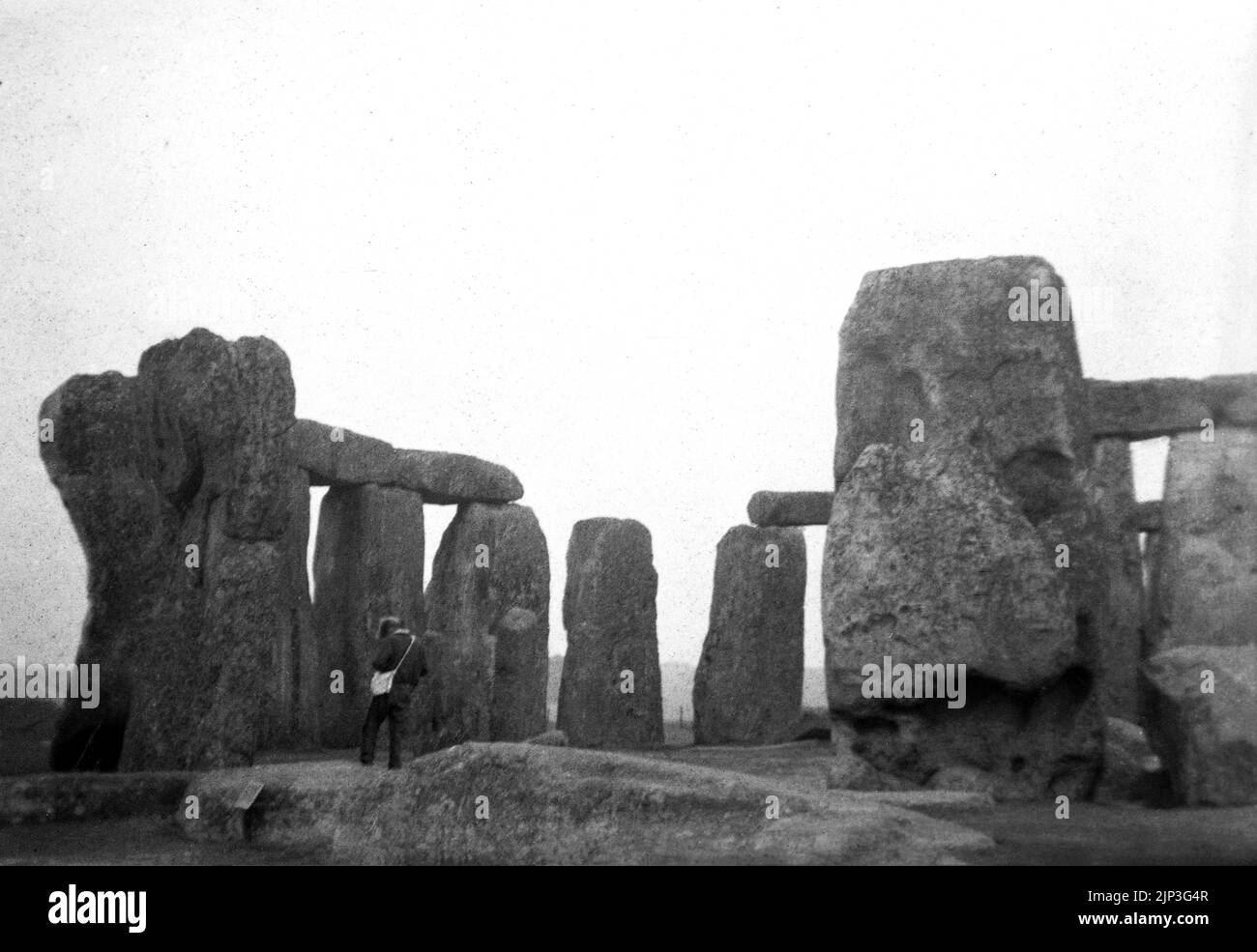 1956, historique, Stonehenge, un monument préhistorique sur la plaine de Salisbury, Wiltshire, Angleterre, Royaume-Uni. La photo montre un homme debout avec un sac à bandoulière par les anciennes pierres sarsen. Banque D'Images