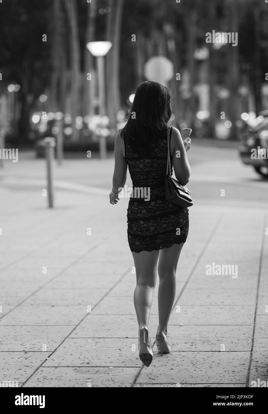 Une échelle de gris d'une jolie femme marchant dans la rue Banque D'Images