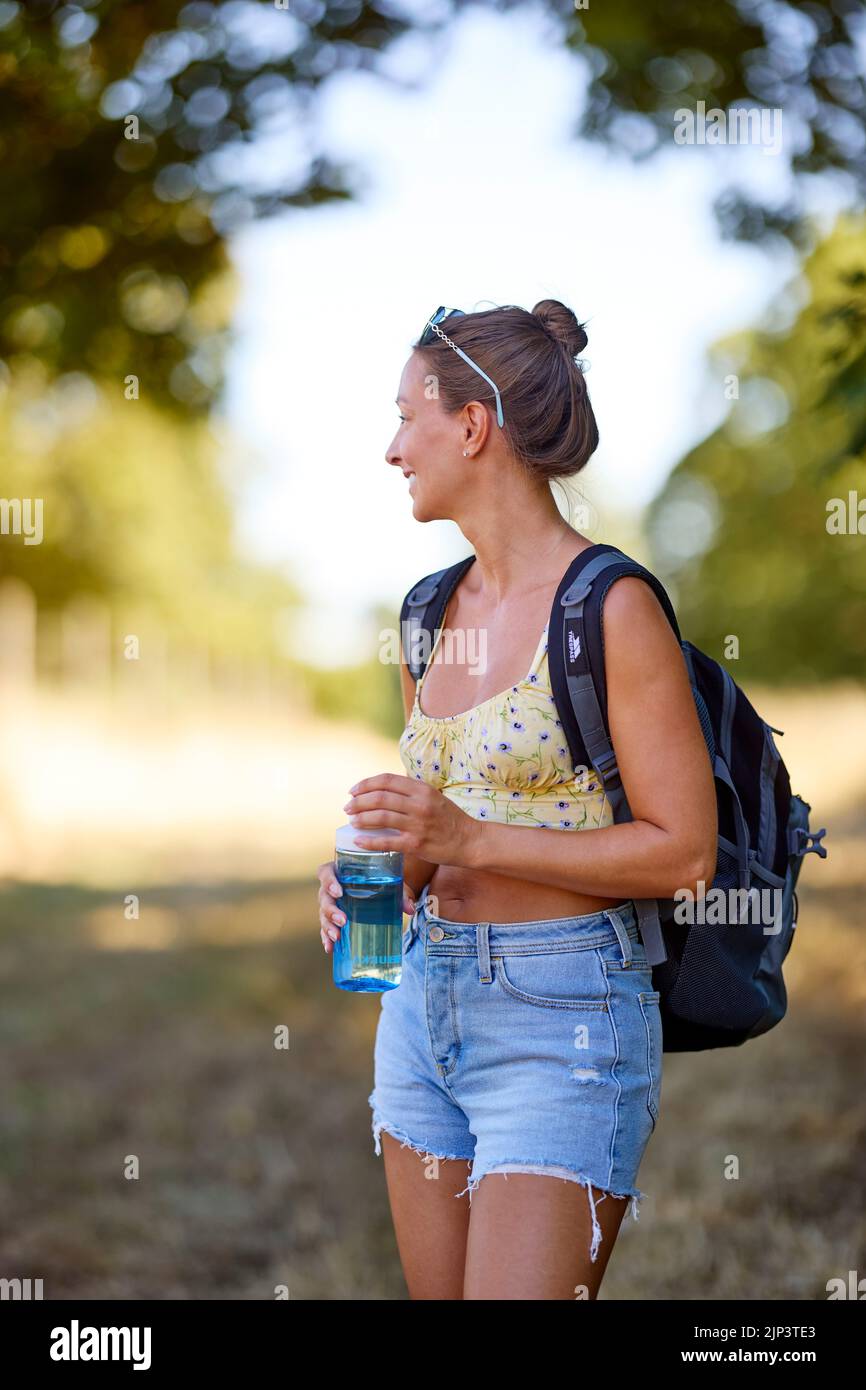 Femme se détendant à l'extérieur avec une bouteille d'eau Banque D'Images