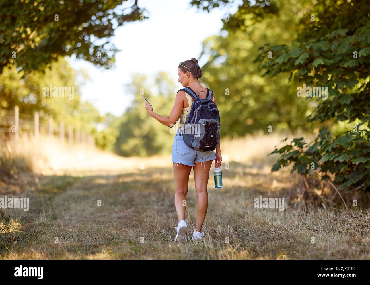 Femme marchant à l'extérieur regardant son téléphone Banque D'Images