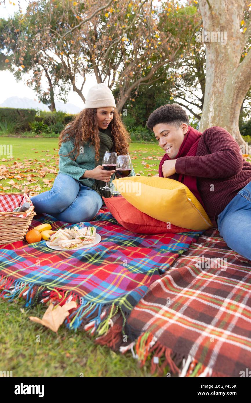 Image verticale d'un couple heureux et varié qui pique-nique dans le parc d'automne Banque D'Images