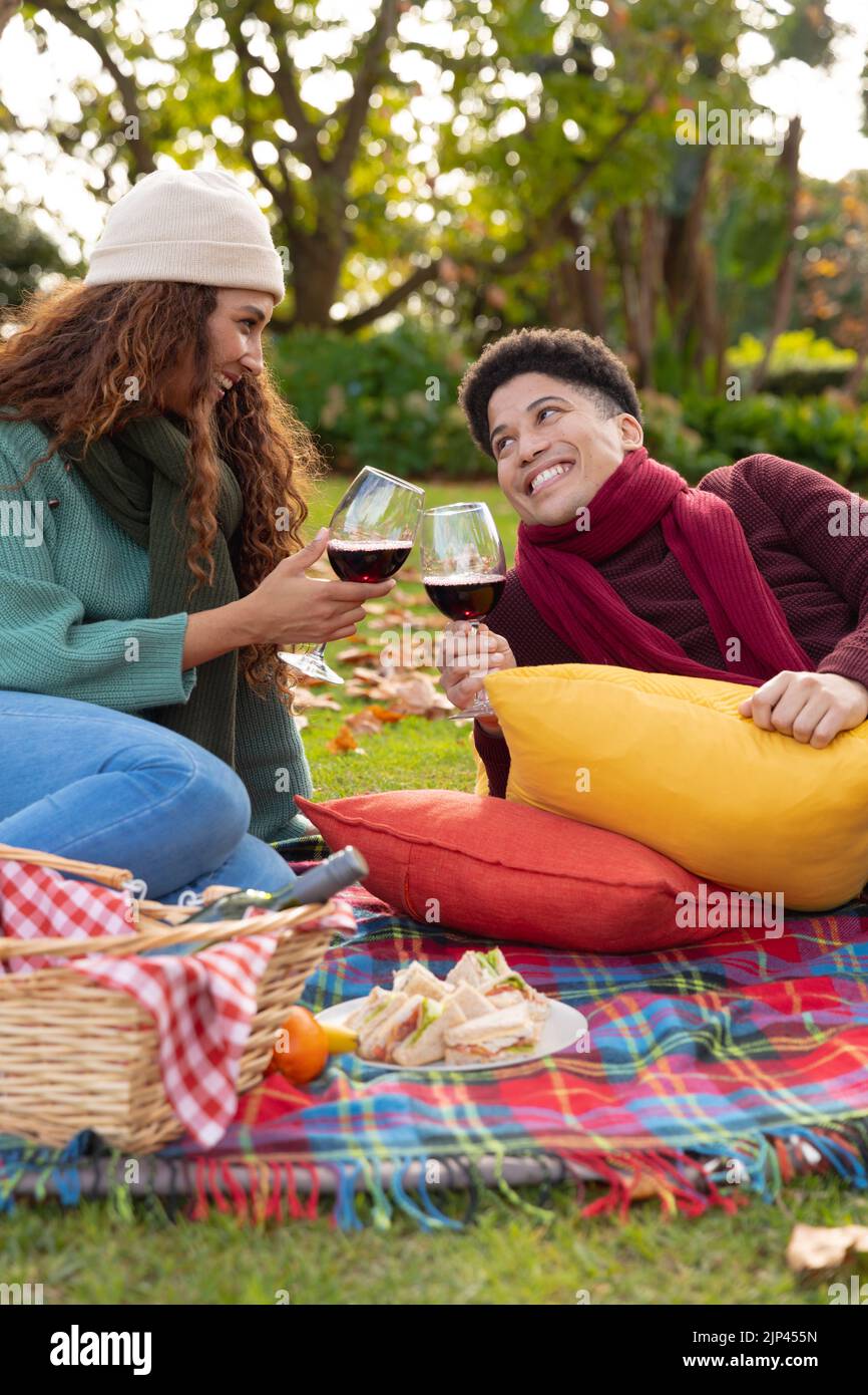 Image verticale d'un couple heureux et varié qui pique-nique dans le parc d'automne Banque D'Images
