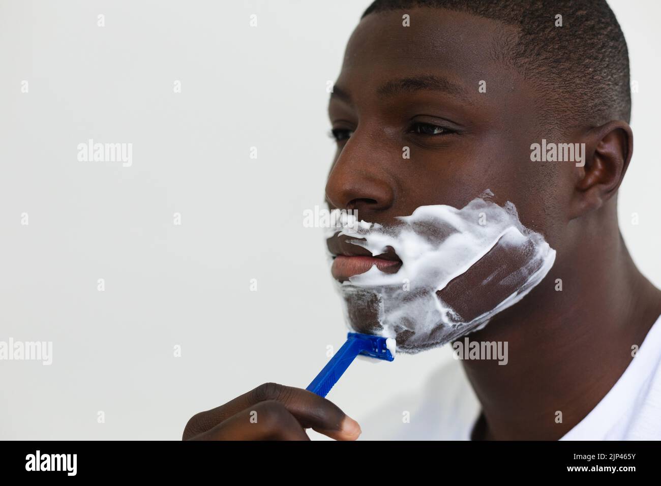 Homme afro-américain se raser le visage dans la salle de bains Banque D'Images