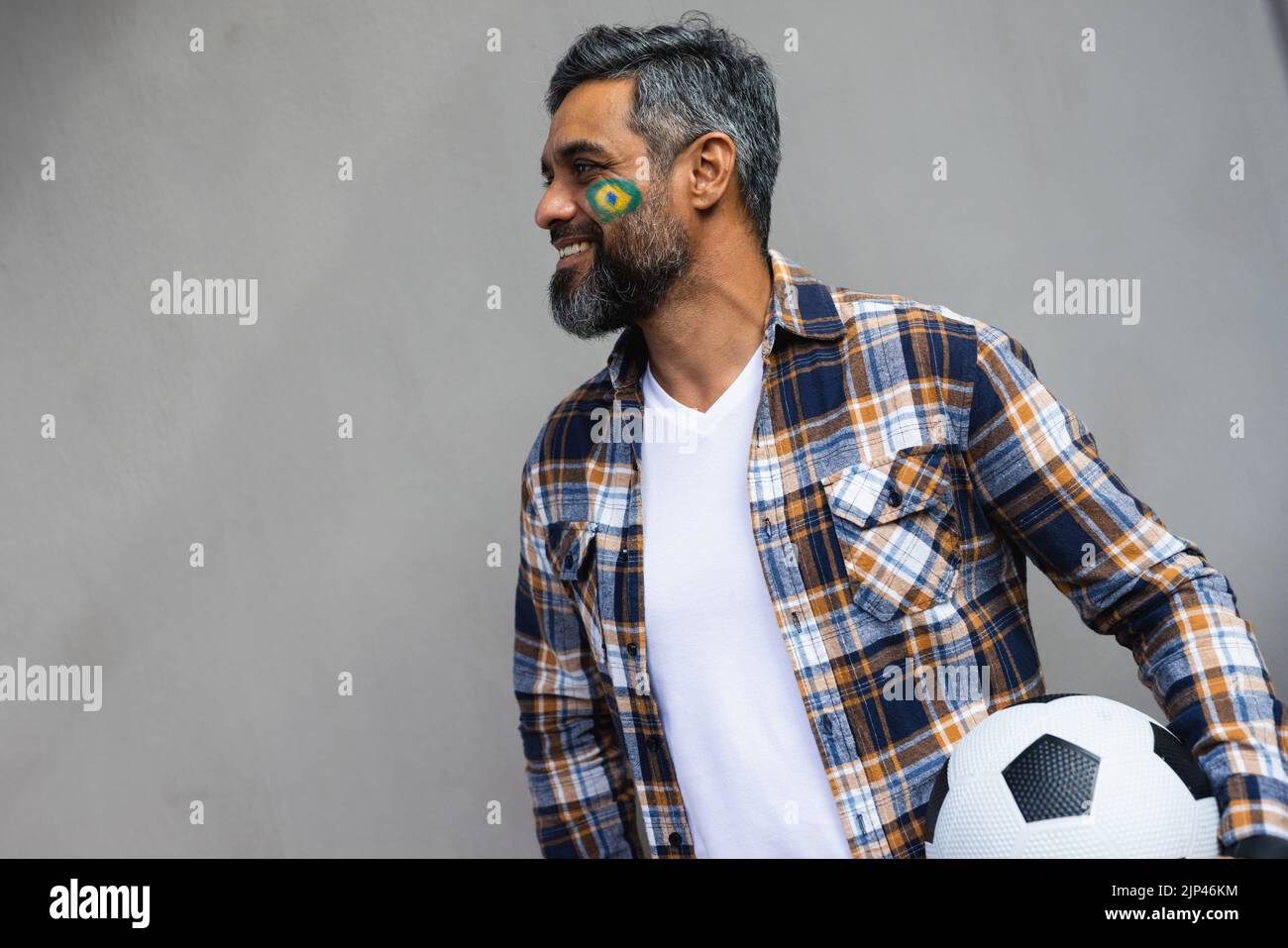 Joyeux biracial homme avec le football et le drapeau du brésil sur sa joue Banque D'Images