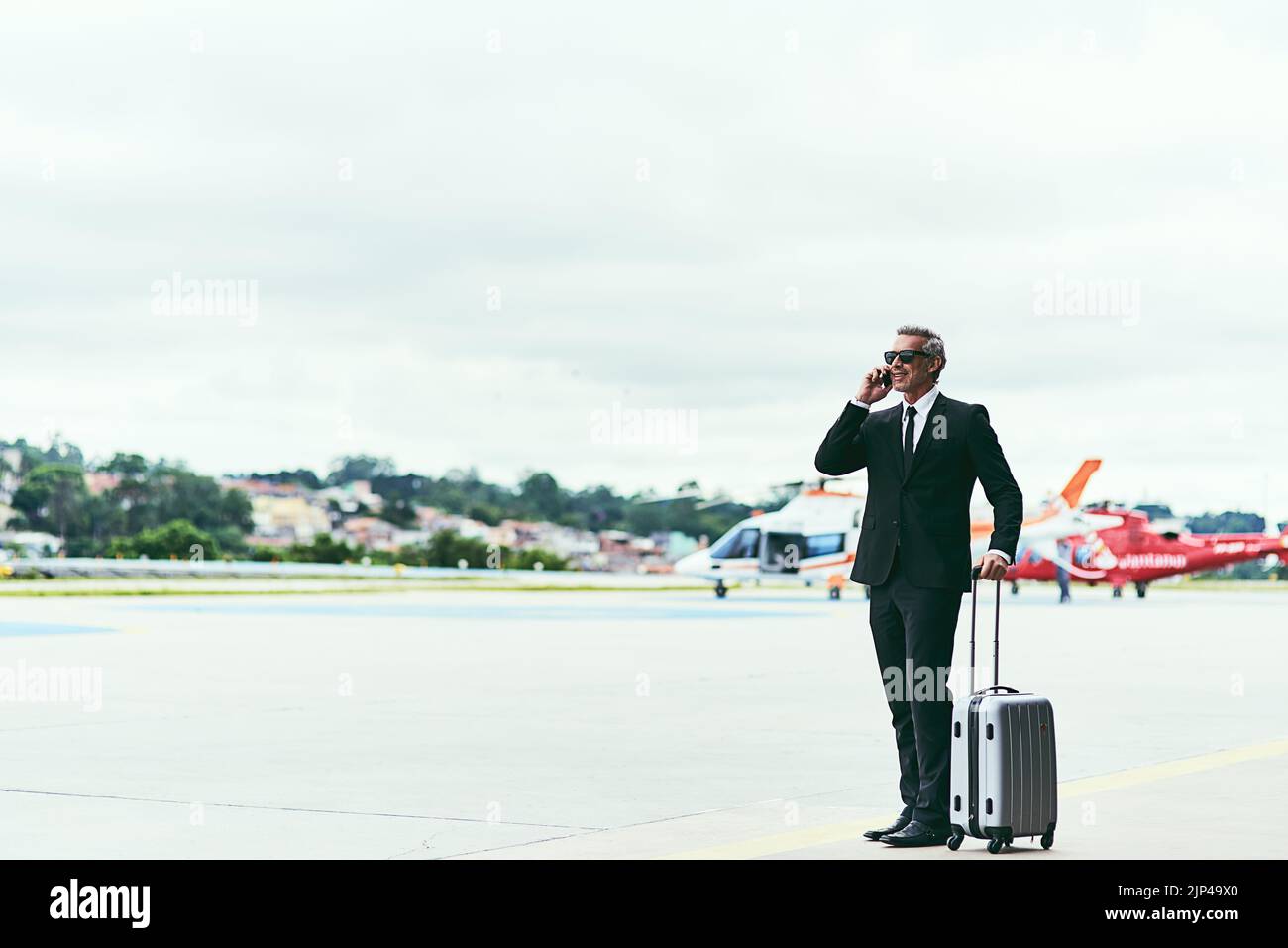 Je viens d'arriver. Photo en longueur d'un beau homme d'affaires mature marchant avec ses bagages devant l'aéroport. Banque D'Images