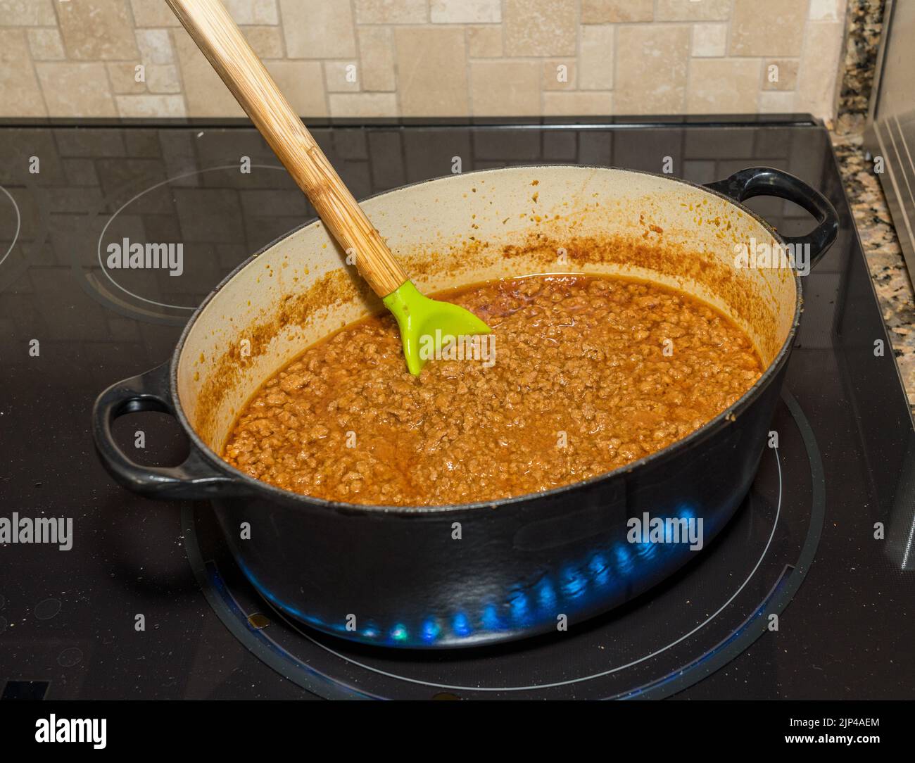 Versez une cuillère dans un pot de ragoût maison ou un ragoût dans un pot en fonte sur une table de cuisson à induction ou une cuisinière Banque D'Images