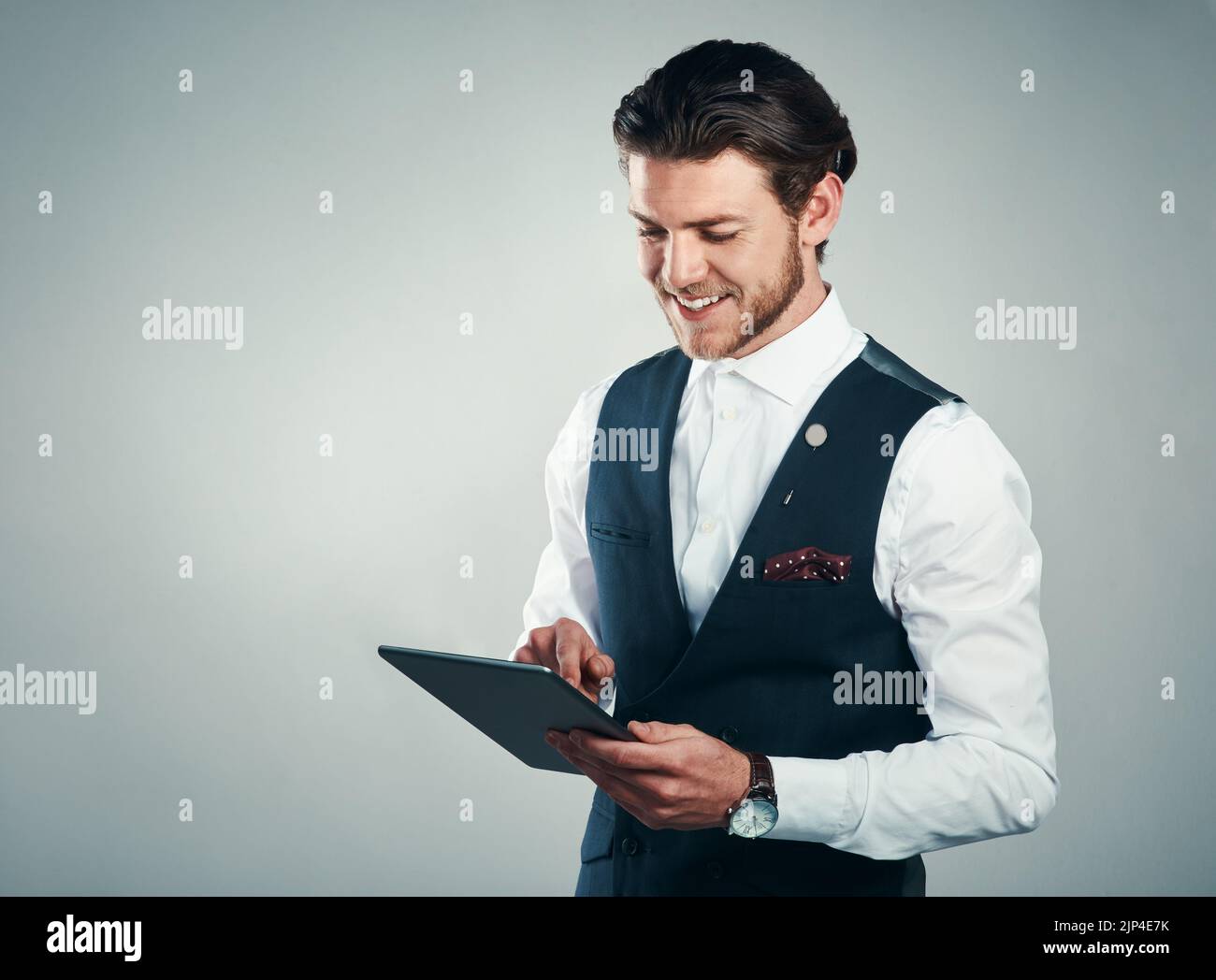 Le succès d'aujourd'hui repose sur la technologie. Studio photo d'un beau jeune homme d'affaires utilisant une tablette sur fond gris. Banque D'Images